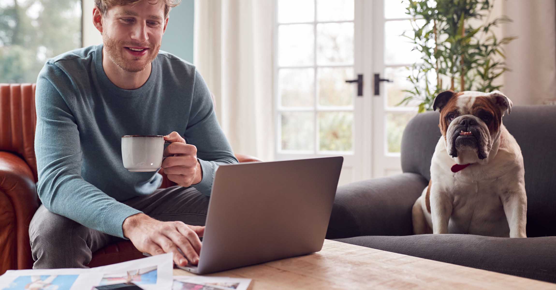 Man with laptop, mug and dog