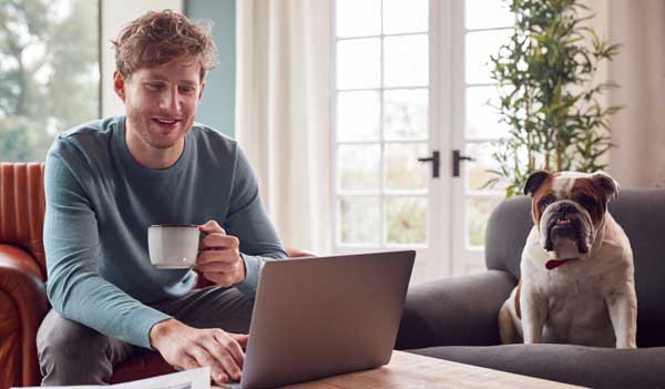 Man with laptop, mug and dog